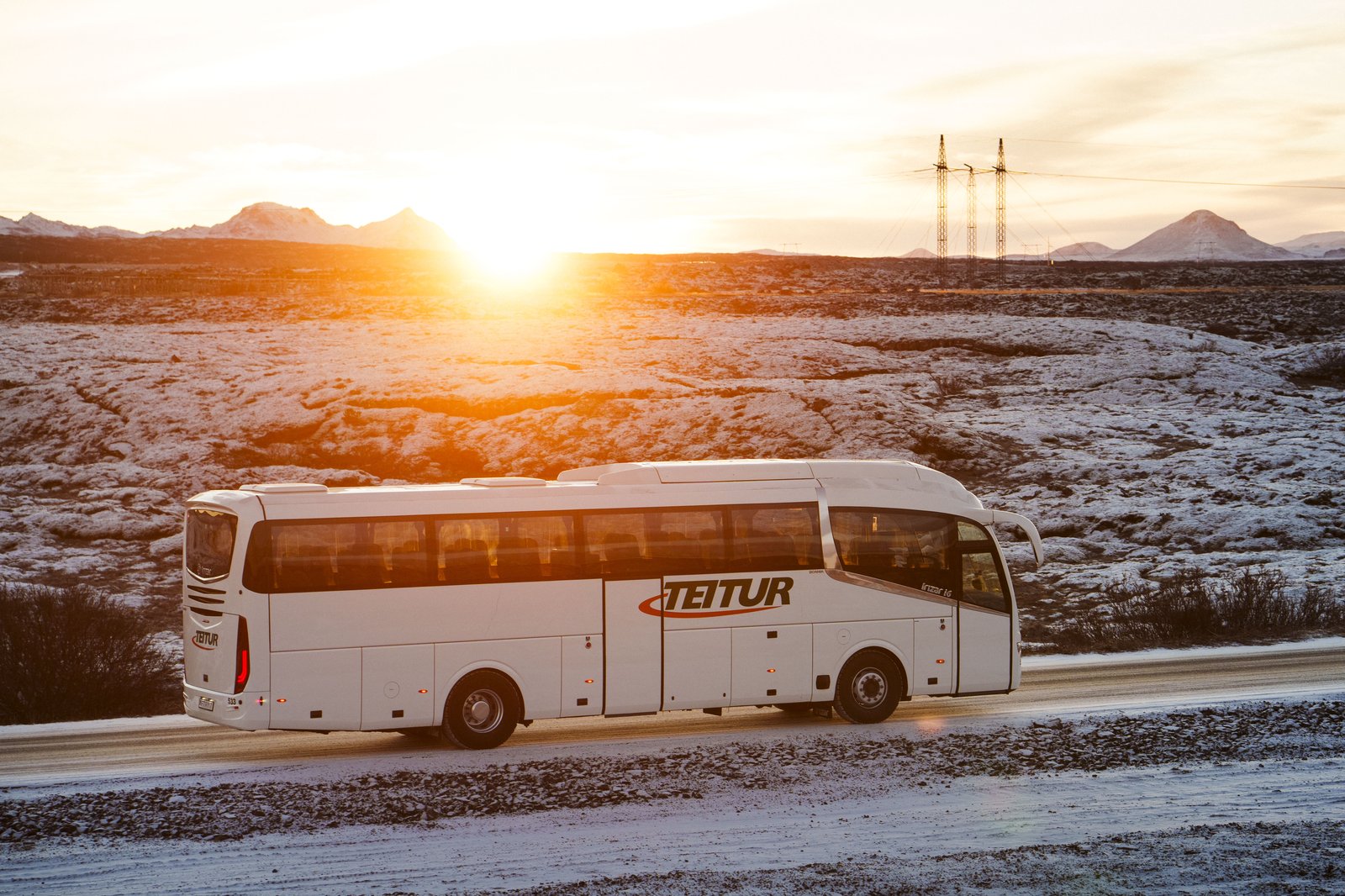 Teitur coach driving into sunrise on snowy road